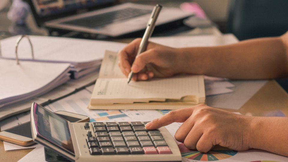Persona haciendo cuentas con una calculadora para el certificado de IRPF