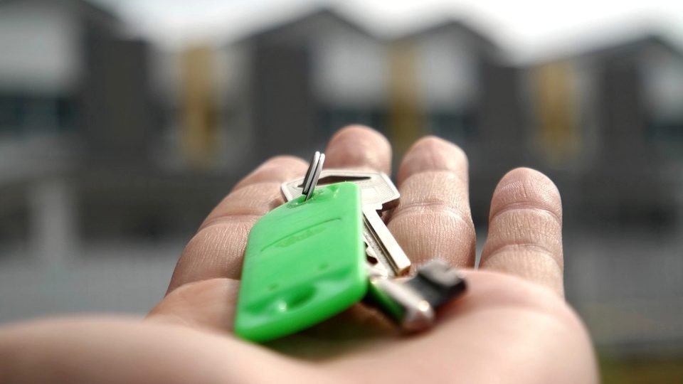 Mano sosteniendo las llaves de una vivienda nueva antes de empadronarse