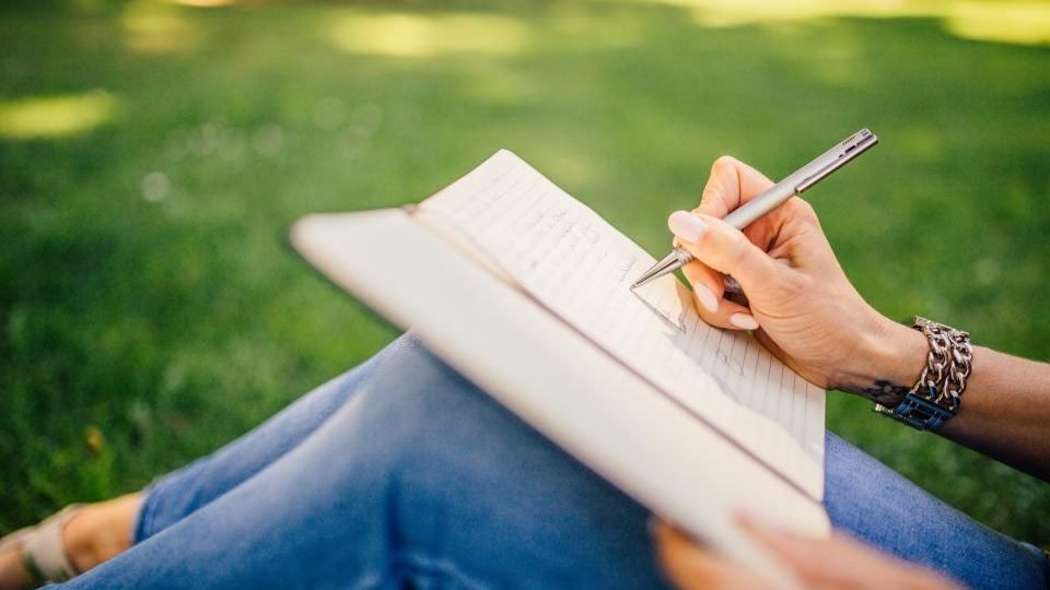 Persona escribiendo en un cuaderno para preparar la solicitud del subsidio por desempleo